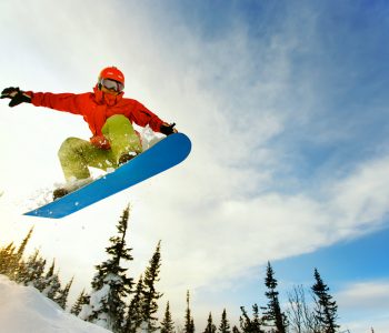 Snowboarder,Jumping,Through,Air,With,Deep,Blue,Sky,In,Background